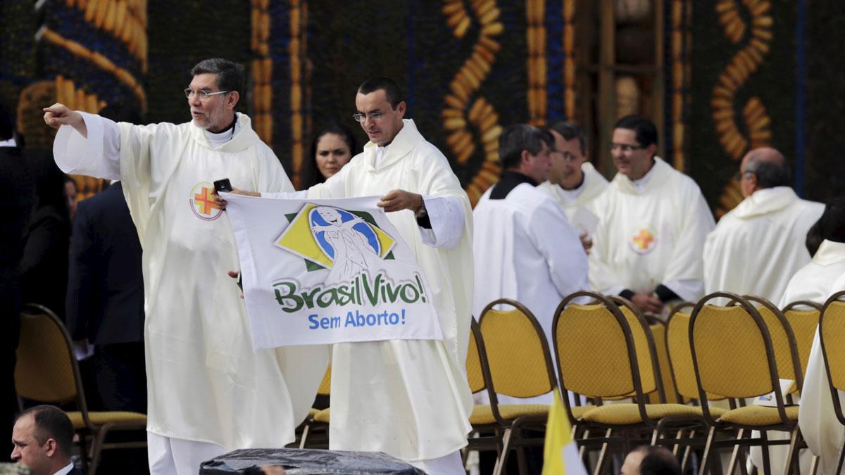 A priest holds up a banner reading "Brazil alive! Without abortion" while standing near an altar where Pope Francis later celebrated mass.