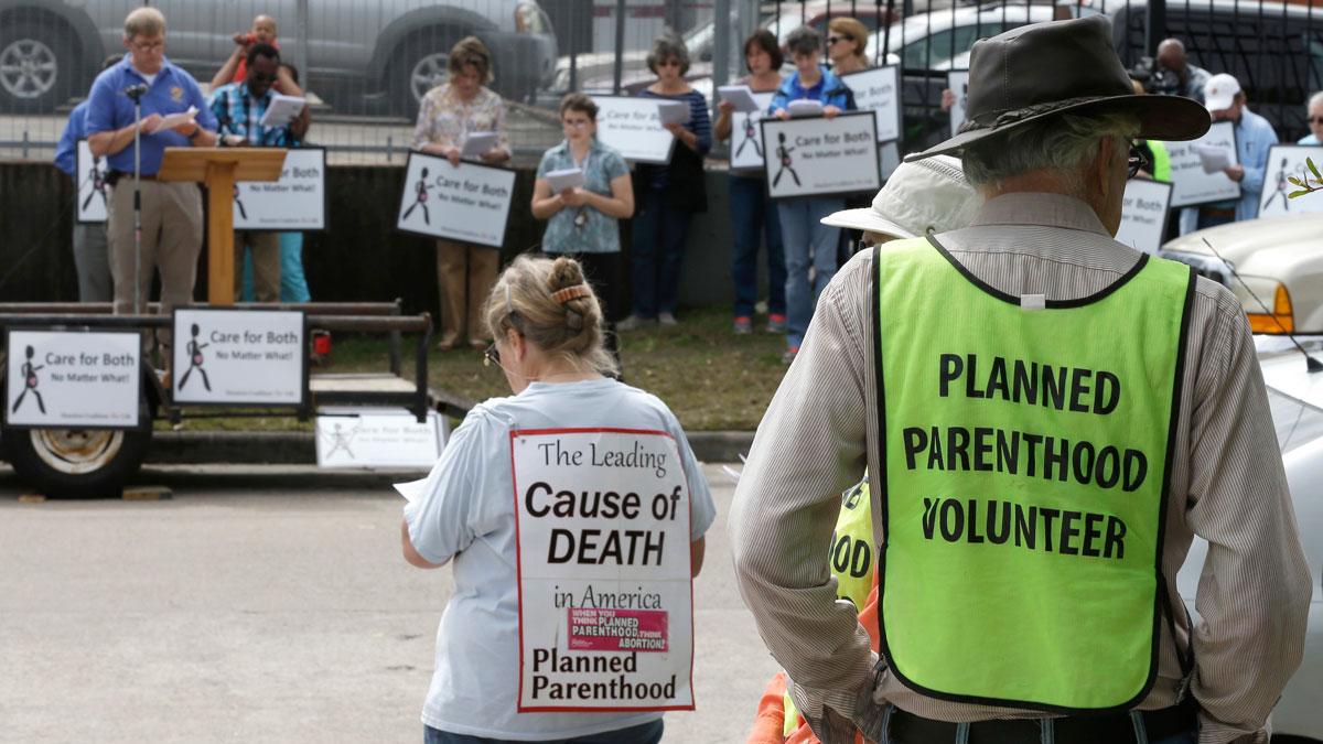 Planned Parenthood volunteers keep watch over anti-abortion protesters outside Planned Parenthood Wednesday, March 2, 2016, in Houston. The Supreme Court appeared sharply divided Wednesday over Texas abortion clinic regulations in its biggest abortion cas