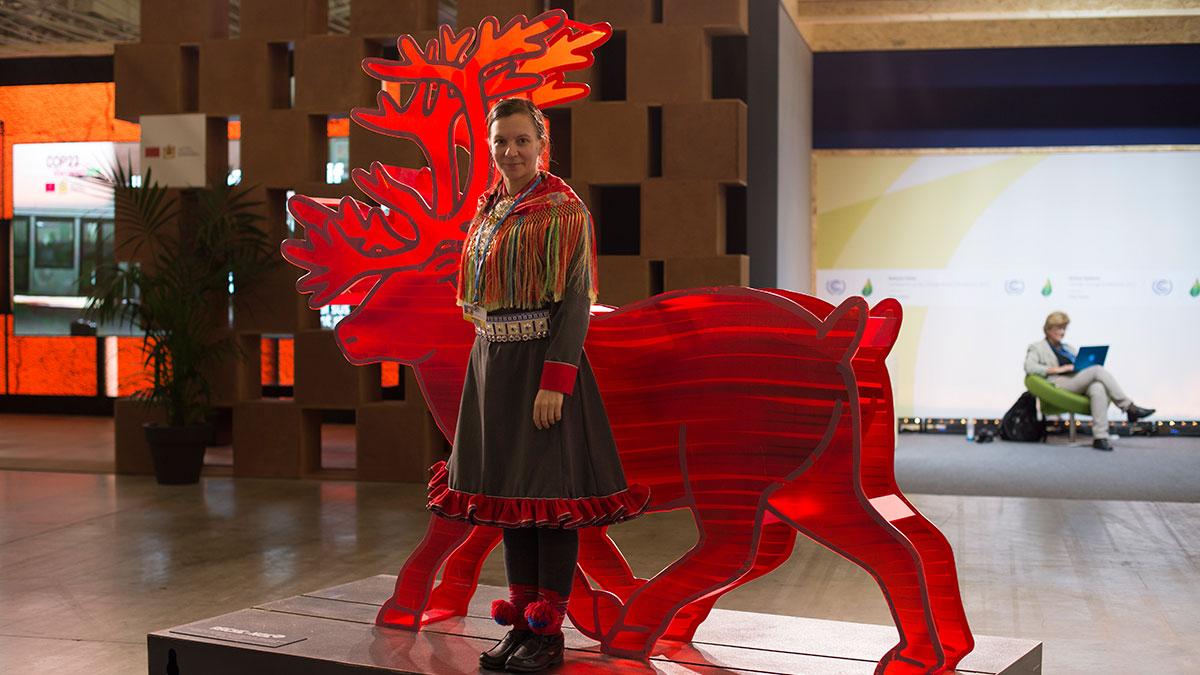 Aile Javo stands in front of a plastic reindeer at COP21.