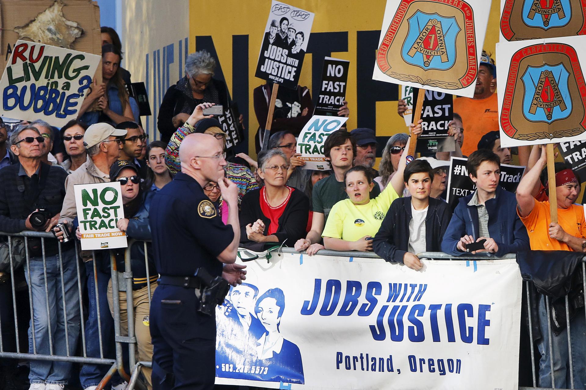 Protesters, many against the fast track trade authority of the Trans-Pacific Partnership trade agreement, rally outside a hotel in Portland, Oregon.