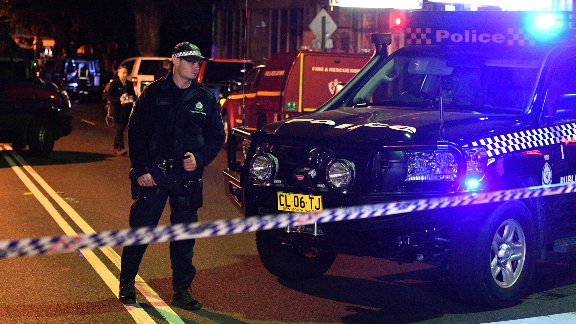 Police man stands at a check point next to a police car in the Sydney inner suburb of Surry Hills