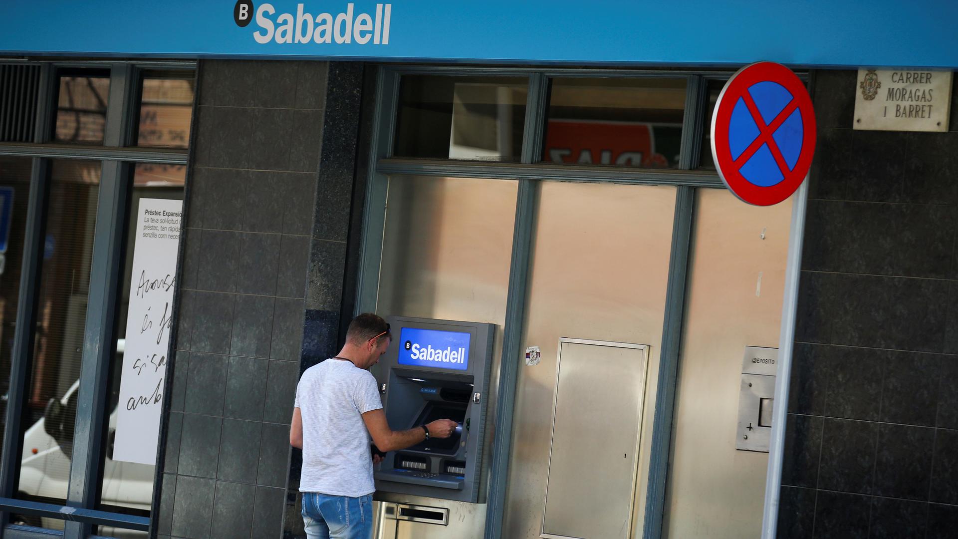 A man uses a cashpoint at a Sabadell bank branch in Pineda de Mar, north of Barcelona.