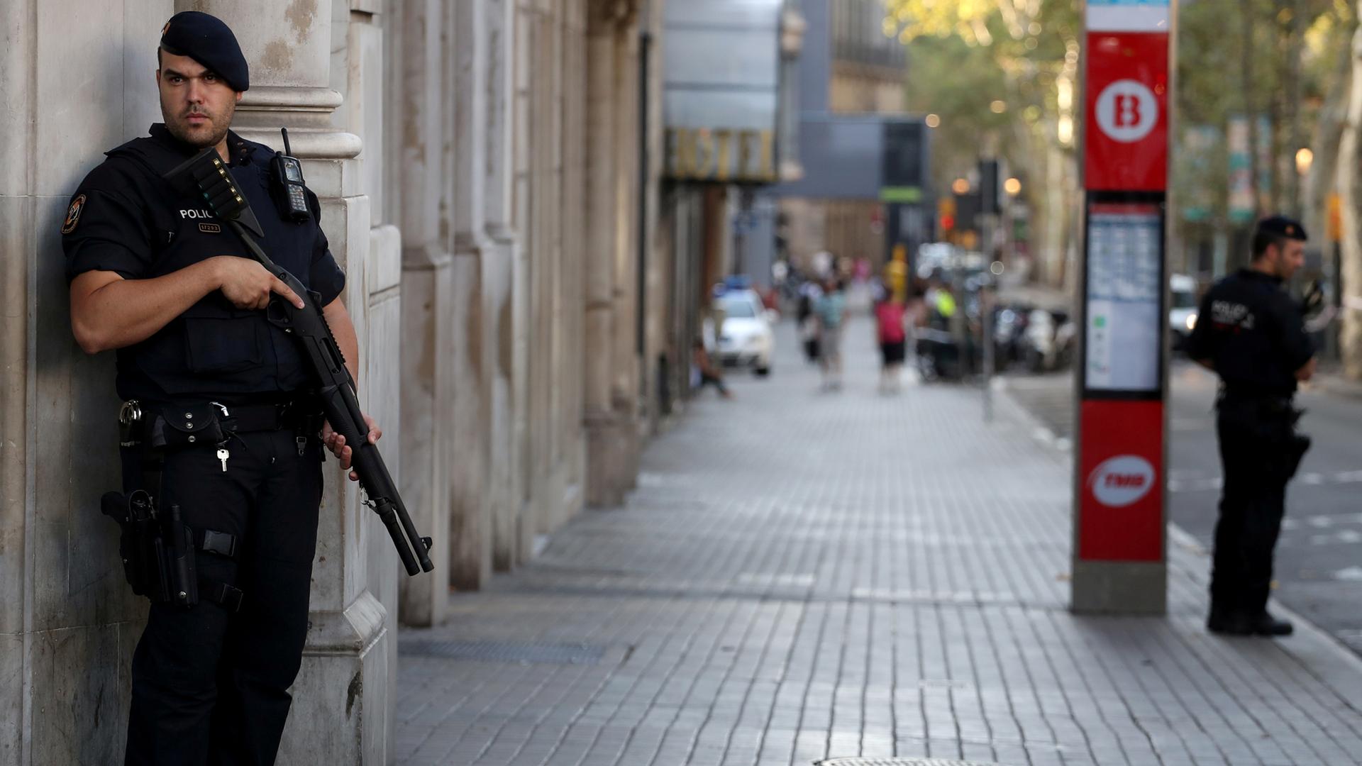 Armed Catalan Mossos d'esquadra officers stand guard at Las Ramblas street where a van crashed into pedestrians in Barcelona. 