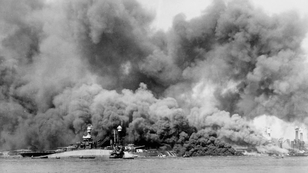‘Battleship Row’ after the Japanese attack on Pearl Harbor on 7 December 1941. The capsized USS Oklahoma is visible in the foreground, behind her is USS Maryland, while USS West Virginia burns furiously on the right.