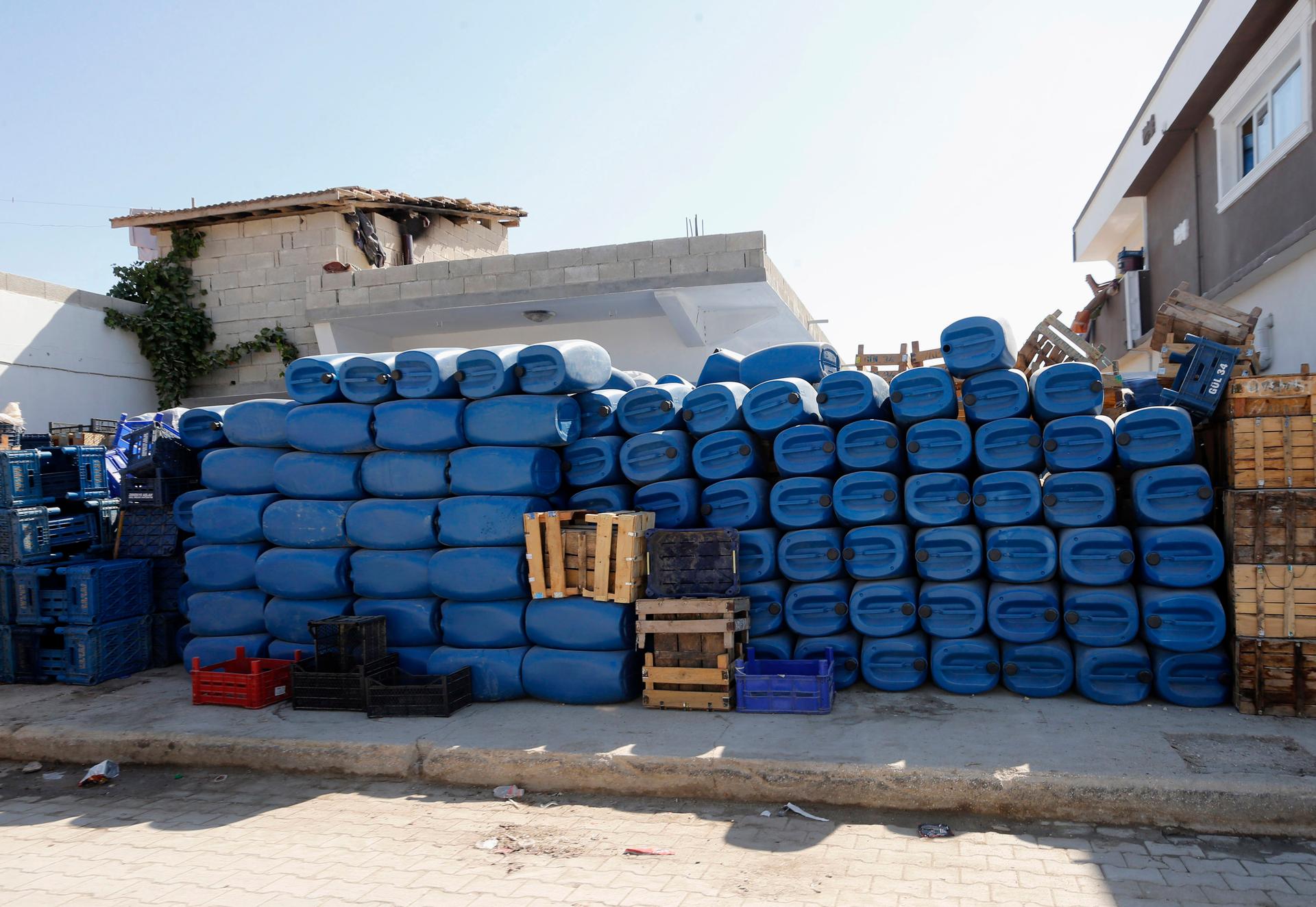 Blue jerry cans, usually used by smugglers ferrying oil from Syria to Turkey, are stacked for sale in front of a shop in the Turkish border town of Hacipasa.