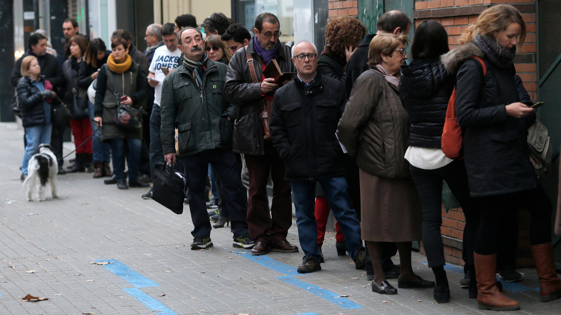 People wait a line as long as three business fronts to vote in Catalonia's regional elections.