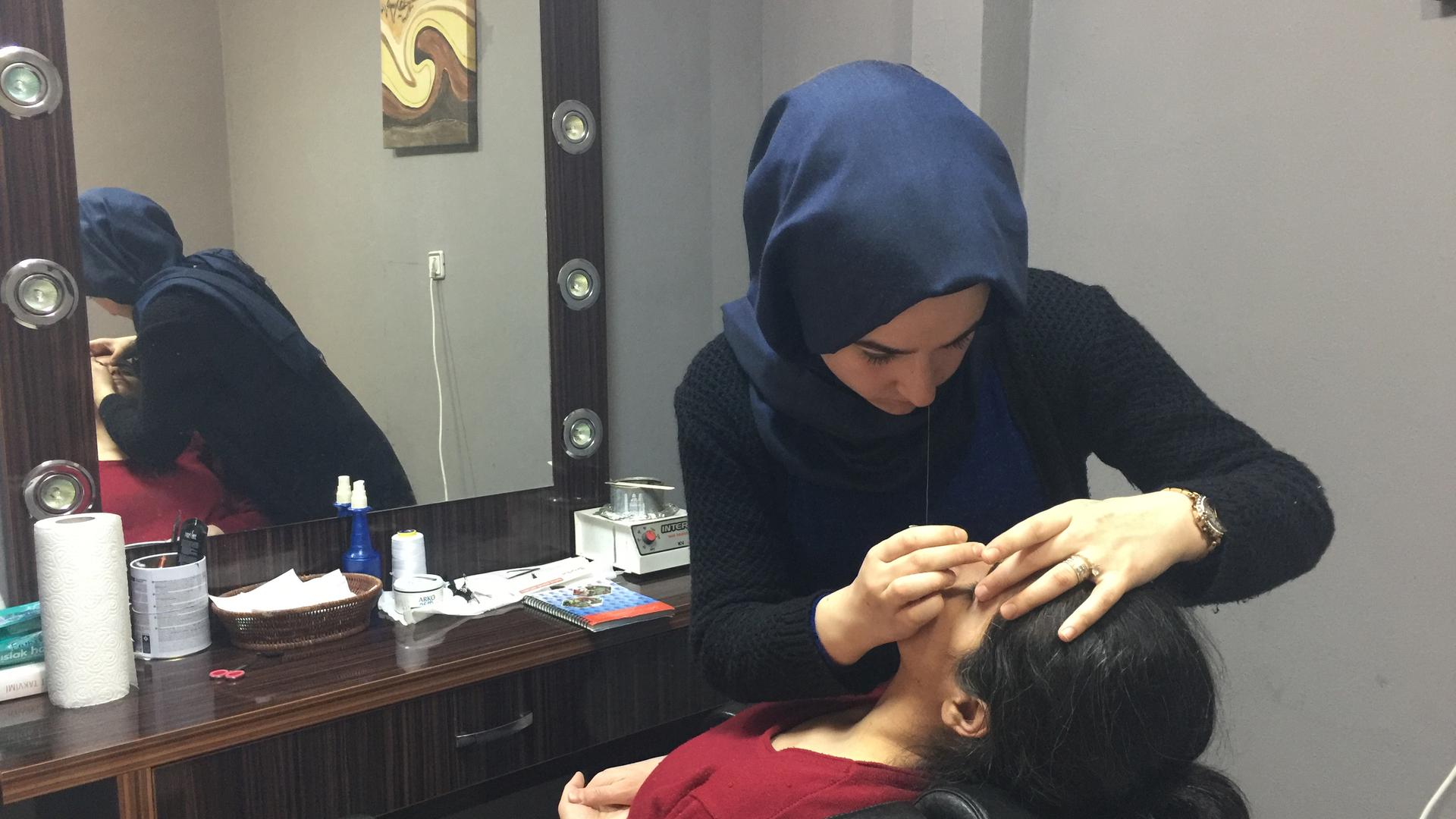 Elif Koc, 18, shapes a customer's eyebrows at the Twins salon in Istanbul. Kroc is voting yes on Sunday's referendum. But she says the issue is dividing her family.