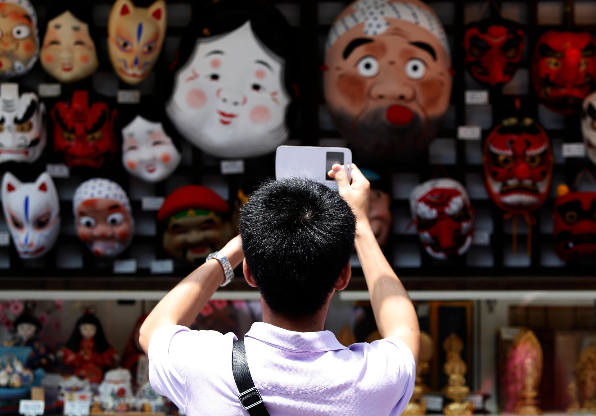 A tourist from China takes pictures of Japanese traditional masks at a souvenir shop in Asakusa district in Tokyo.