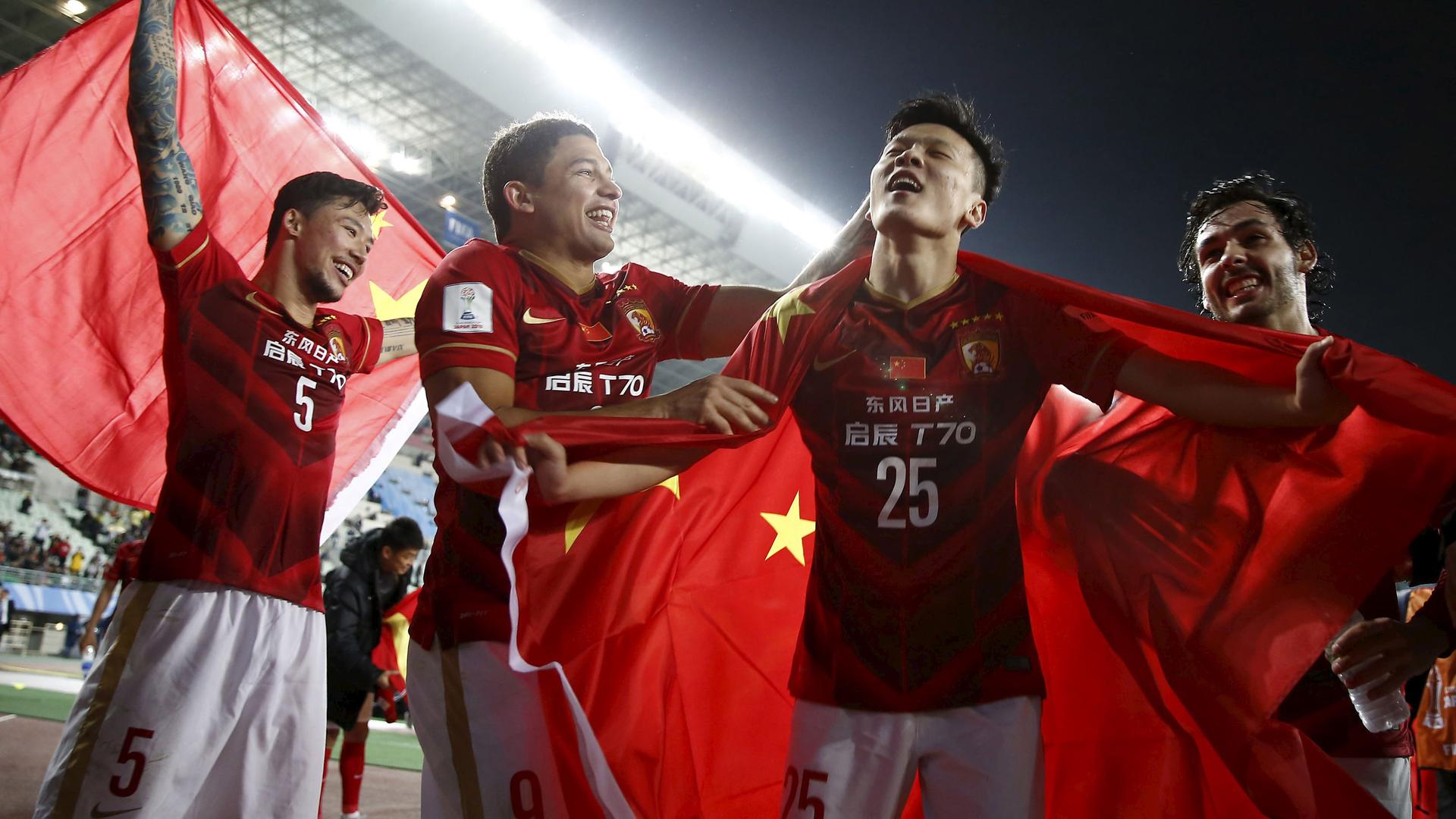 Zou Zheng (25) of China's Guangzhou Evergrande holds Chinese national flag as he celebrates with teammates after winning their Club World Cup quarter-final soccer match against Mexico's Club America during in Osaka, western Japan, December 13, 2015.