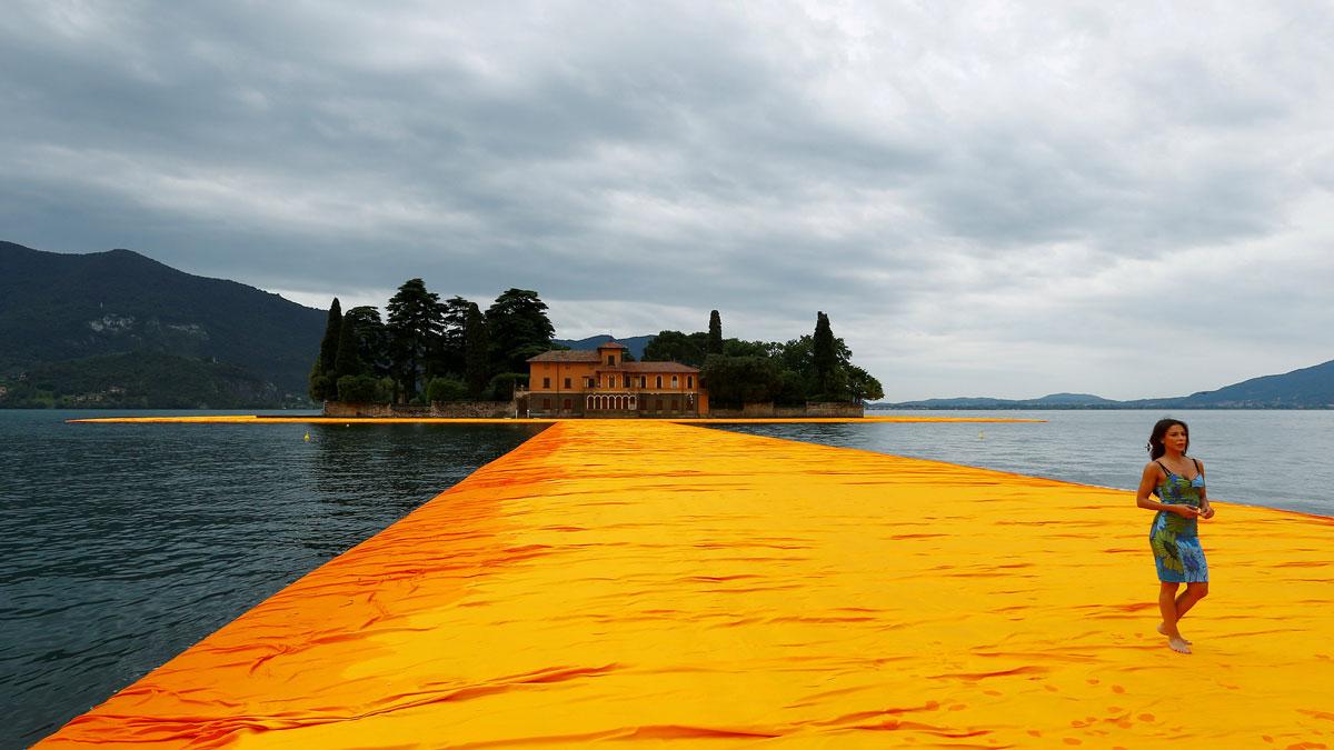 A woman walks on the installation "The Floating Piers" by Bulgarian-born artist Christo Vladimirov Yavachev known as Christo, on Lake Iseo, northern Italy.