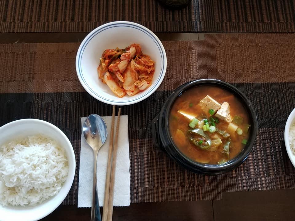 Dishes of rice, stew and kimchi on a wooden table