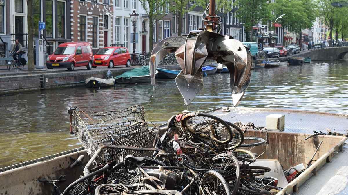 Bike fishermen use a giant claw to remove bikes and other detritus from the Amsterdam canals. The bikes are deposited on a trash barge, and later recycled for scrap.