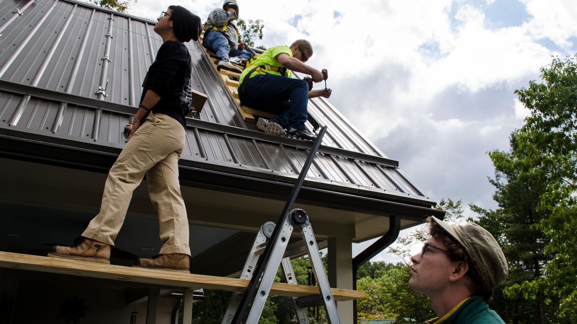 Solar Holler founder Dan Conant, foreground, looks on at the beginning of a solar roof installation in Lewisburg, West Virginia. 