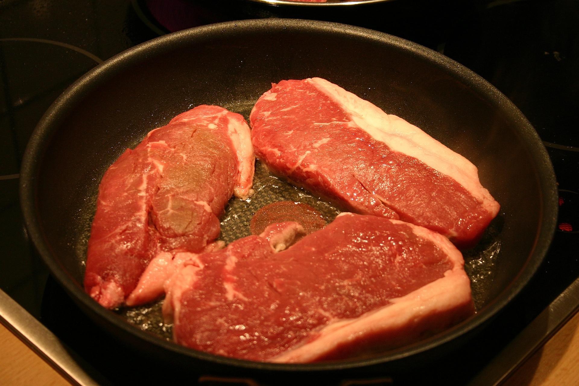 Steaks cooking in a skillet.