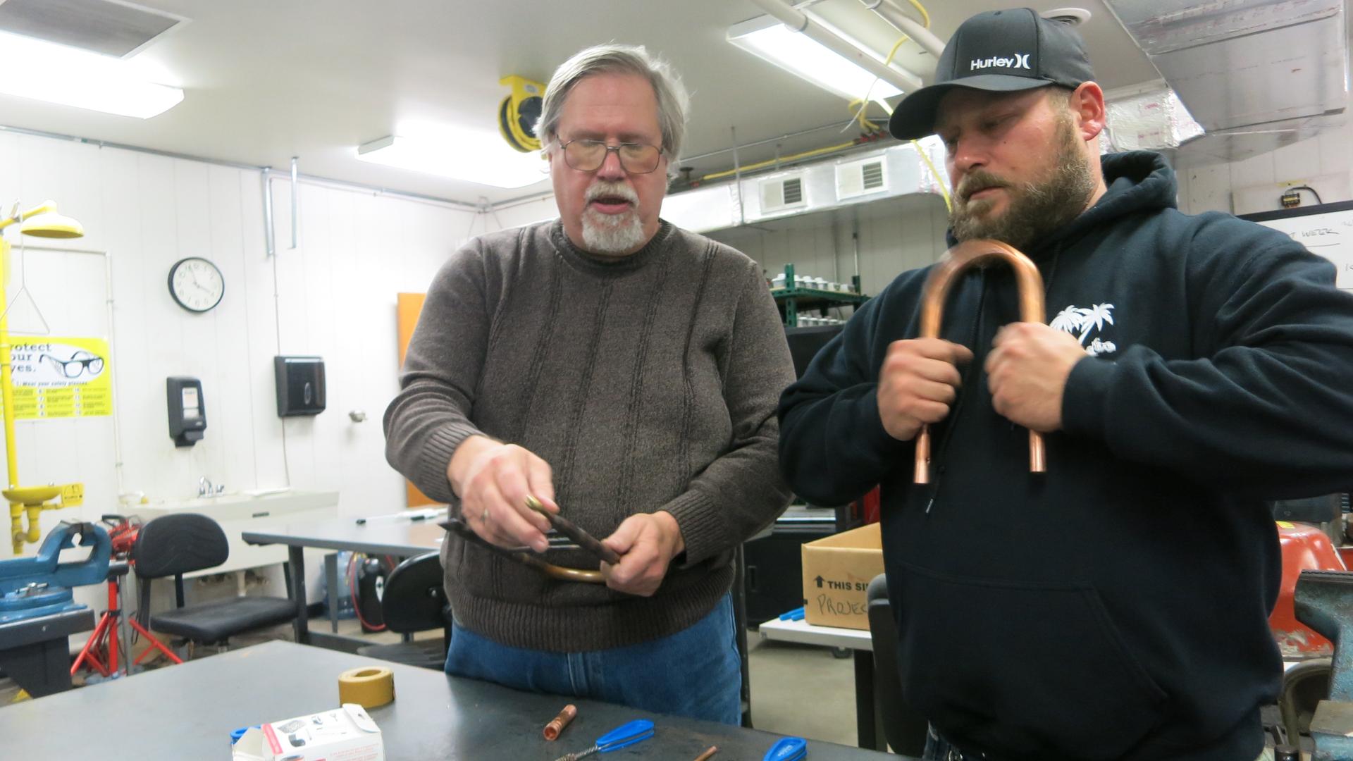 HVAC Instructor Dennis Matney (left) teaches Travis Keppen how to repair pipes in a classroom in Burns Harbor, Indiana. 