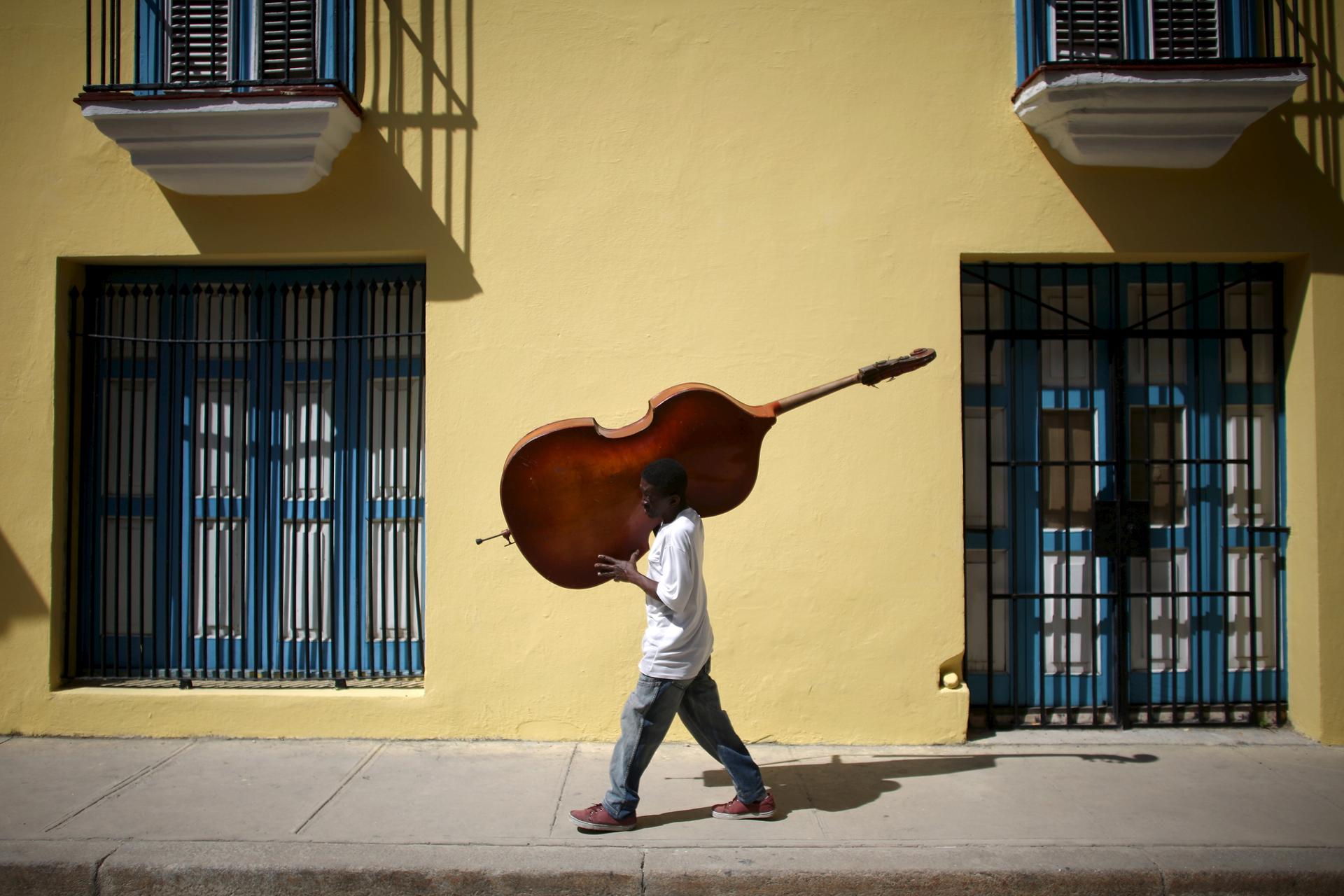 Musician Frilal Ortiz carries a double bass in downtown Havana