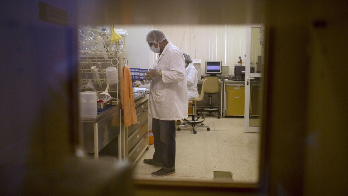 Researchers, seen through a window, work at Cuba's Center for Genetic Engineering and Biotechnology in Havana, 2015.