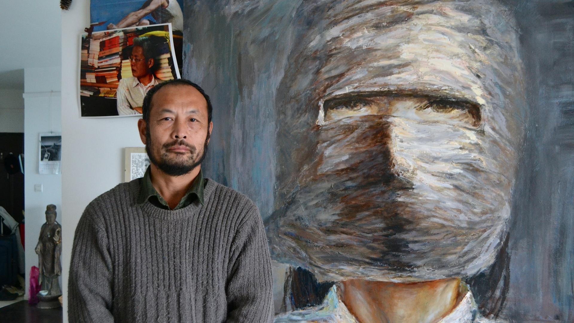 Hu Jie is also a painter, standing here in his Nanjing apartment next to a portrait of one of the subjects of his films, Lin Zhao, a political prisoner who was executed in the late 1960s.