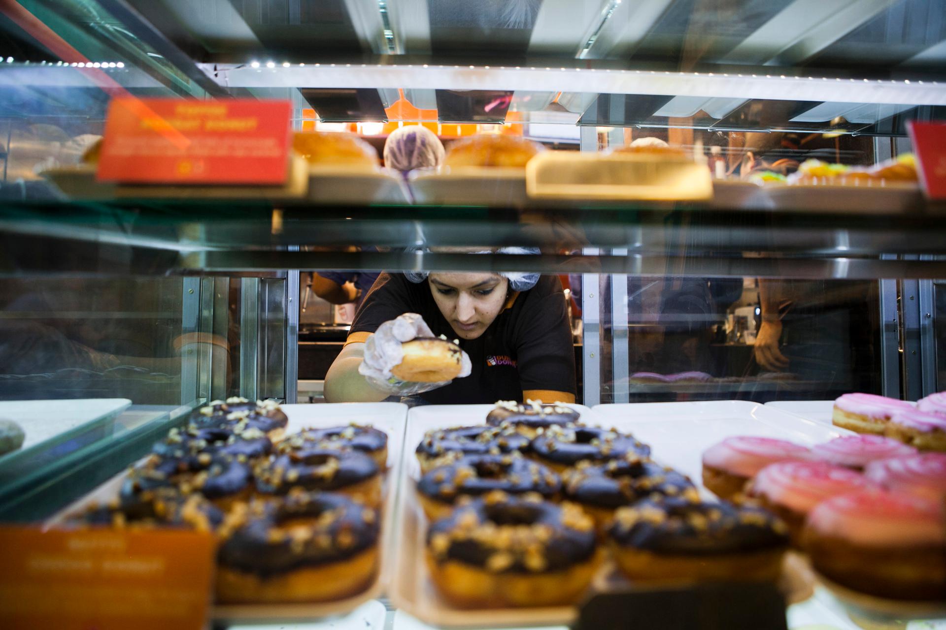 An employee takes a donut from a display cabinet at the Dunkin' Donuts store in New Delhi, India.