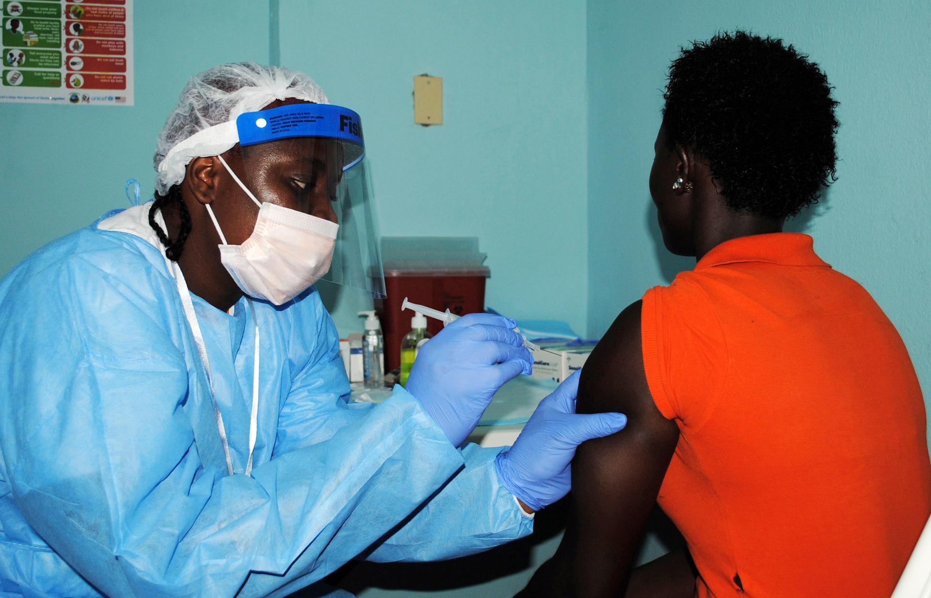 A health worker injects a woman with an Ebola vaccine during a trial in Liberia