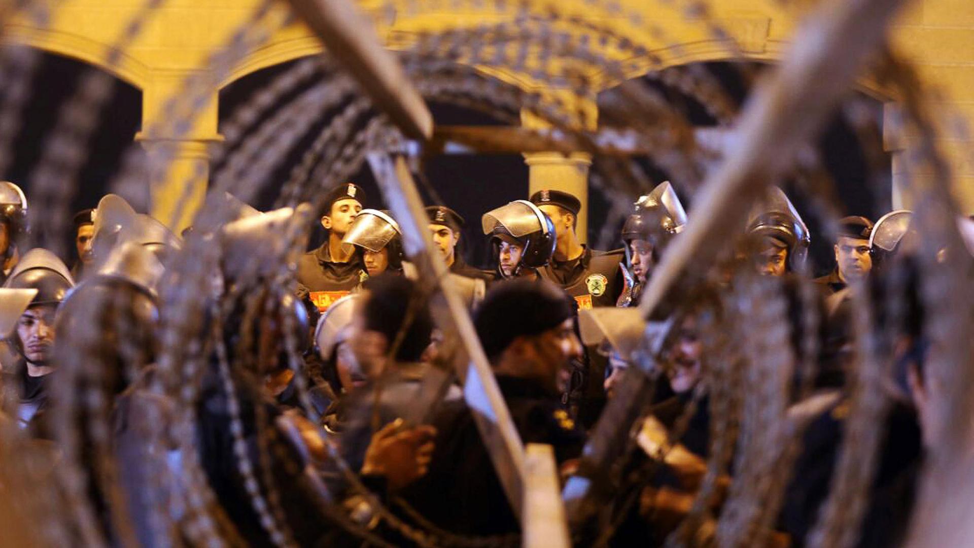 Policemen and soccer fans are seen through barbed wire as fans attempt to enter a stadium to watch a match, on the outskirts of Cairo February 8, 2015.