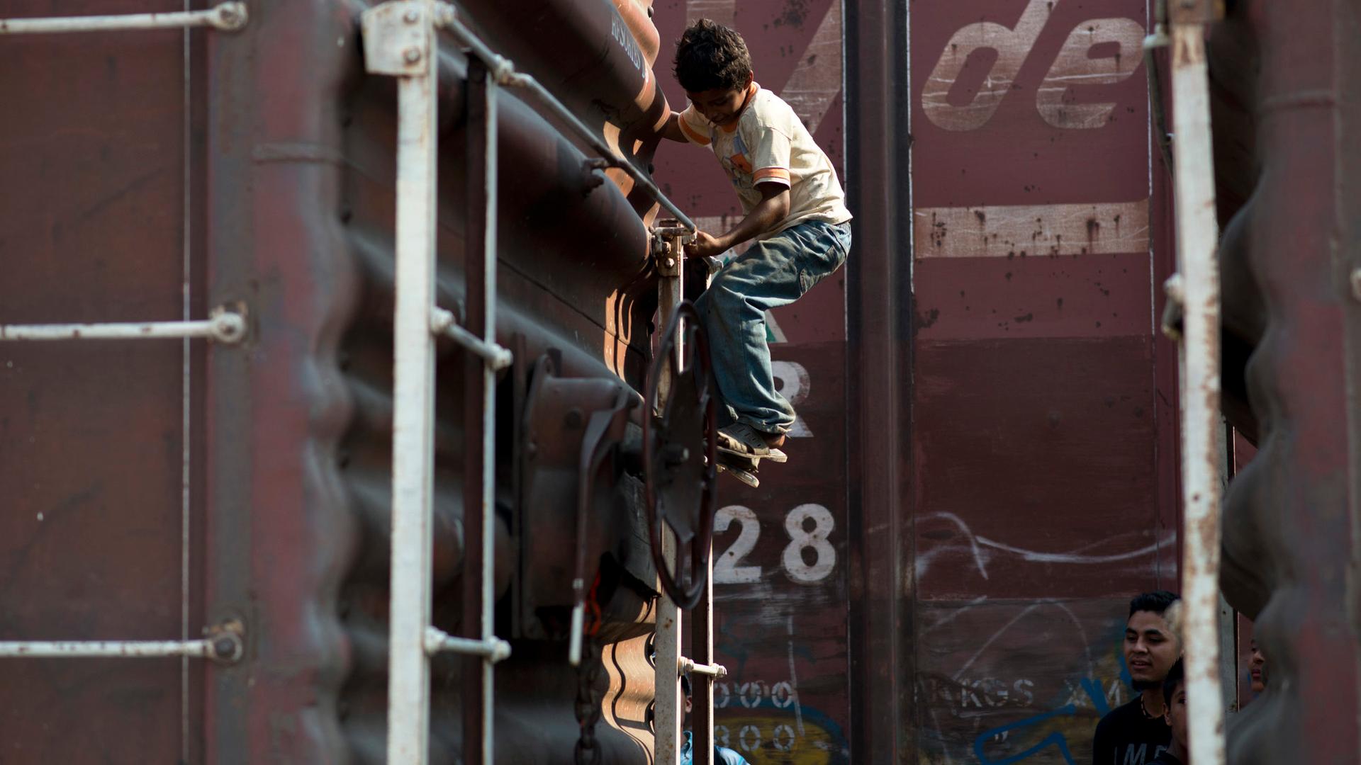 A child boards a freight train near Arriaga, Chiapas, in southern Mexico. Arriaga is the first stop for many Central American migrants making their way to the US.