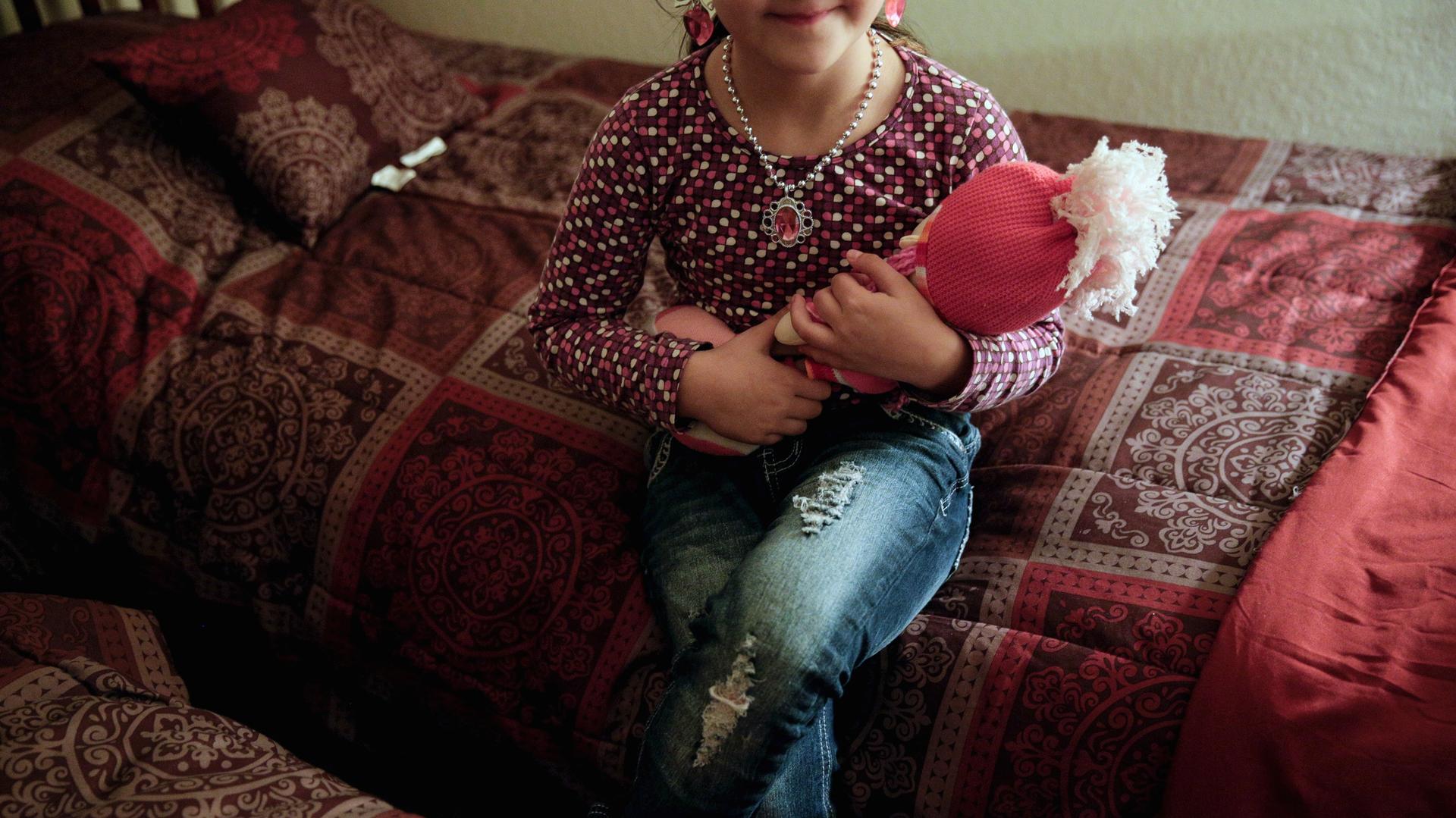 Five-year-old Leen, a Syrian refugee, poses for a portrait with her doll in her Sacramento, California bedroom on November 16, 2015. Her face is not being shown for security reasons. 