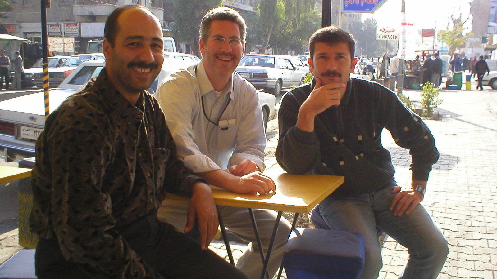 Translator extraordinaire Ayub Nuri on the right, along with reporter Aaron Schachter and their driver Abdulrazzaq Zanjeel at a street cafe in Baghdad in 2003.