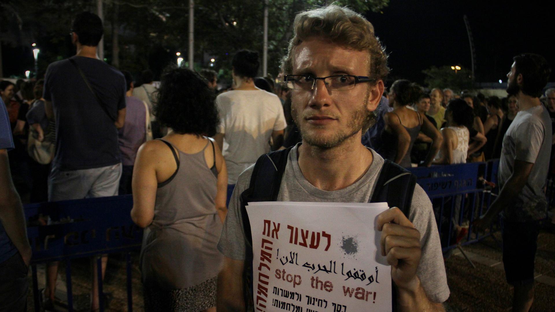 Israeli Yasha Marmer protests against his country’s operation in the Gaza Strip, holding a poster that says “stop the war” in Hebrew, Arabic and English.
