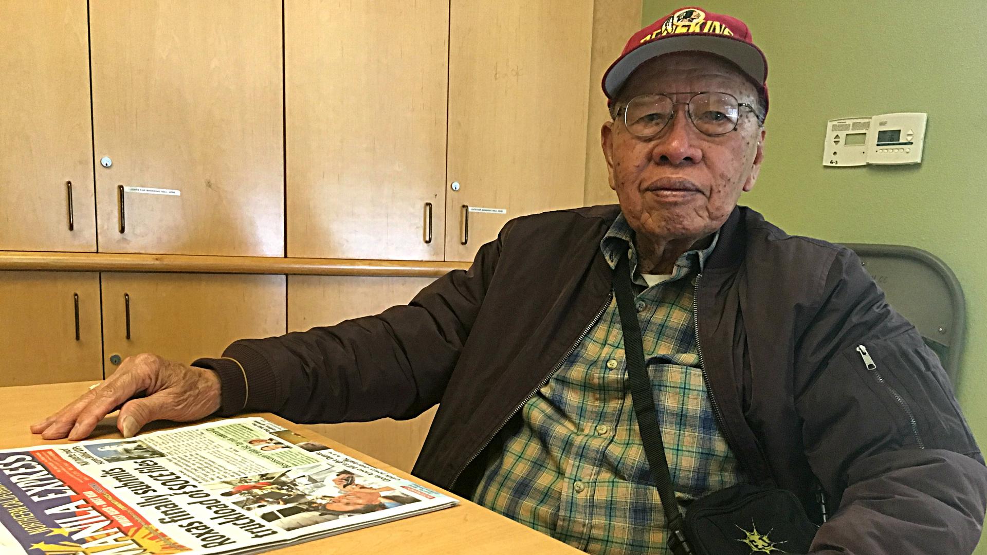 An elderly man sitting at a table with photos
