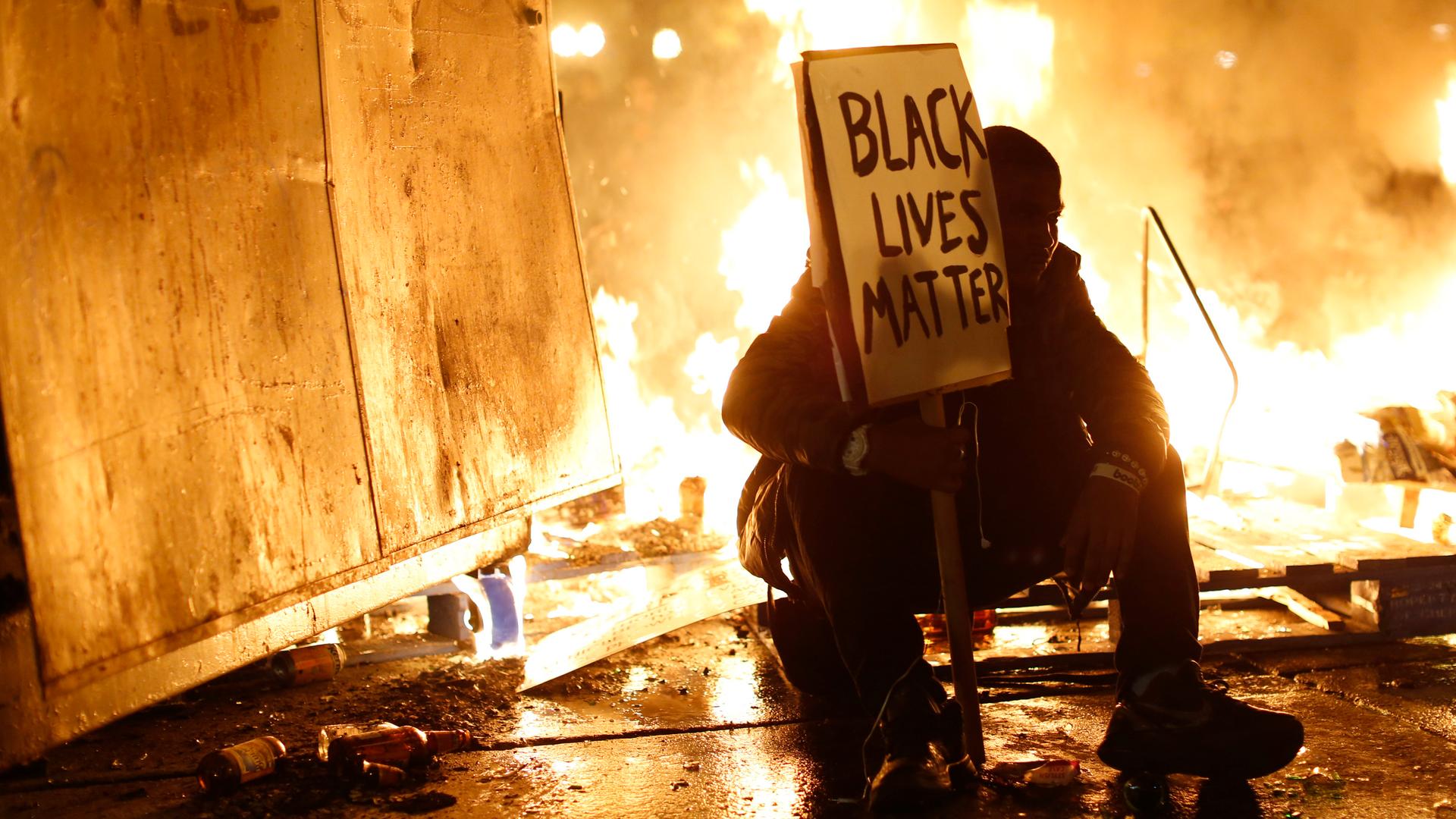 A demonstrator sits in front of a street fire during a demonstration following the grand jury decision in the Ferguson, Missouri shooting of Michael Brown, in Oakland, California on November 25, 2014.