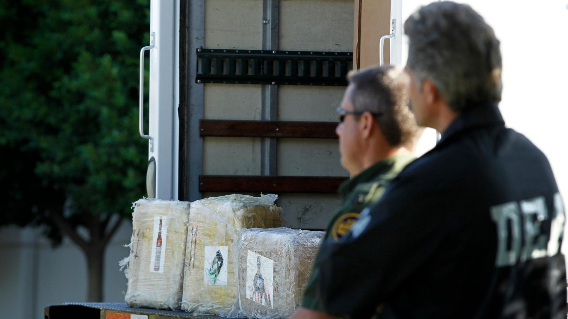 A DEA agent and a US Border Patrol officer stand next to some of the over 14 tons of marijuana seized after discovering a major cross-border drug tunnel linking warehouses in Tijuana, Mexico, and Otay Mesa, California, on November 16, 2011.