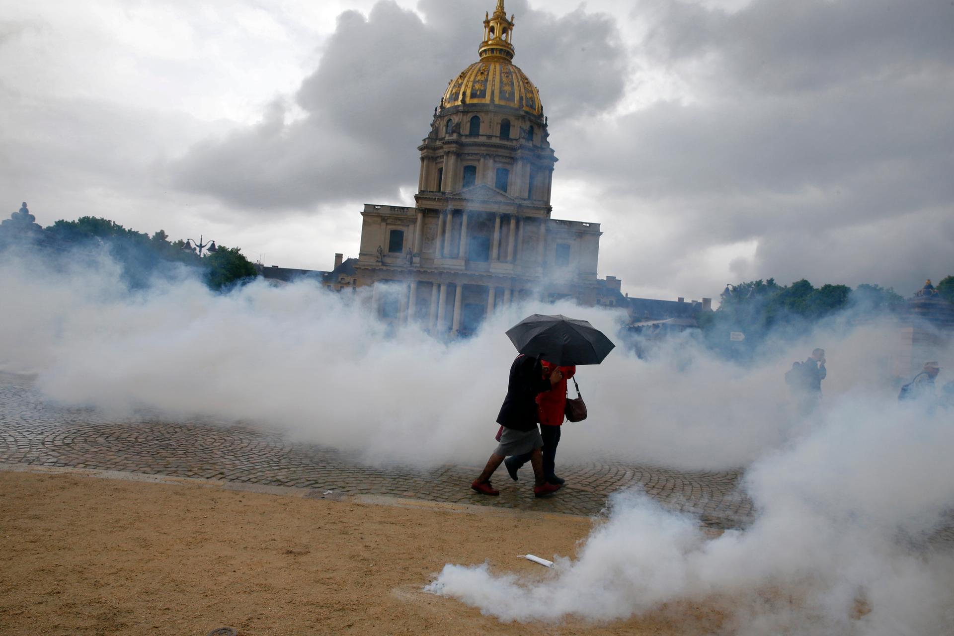 Clouds of tear gas surround people near the Invalides monument during clashes between protesters and French police during a demonstration against French labor law reform in Paris. May 12, 2016.