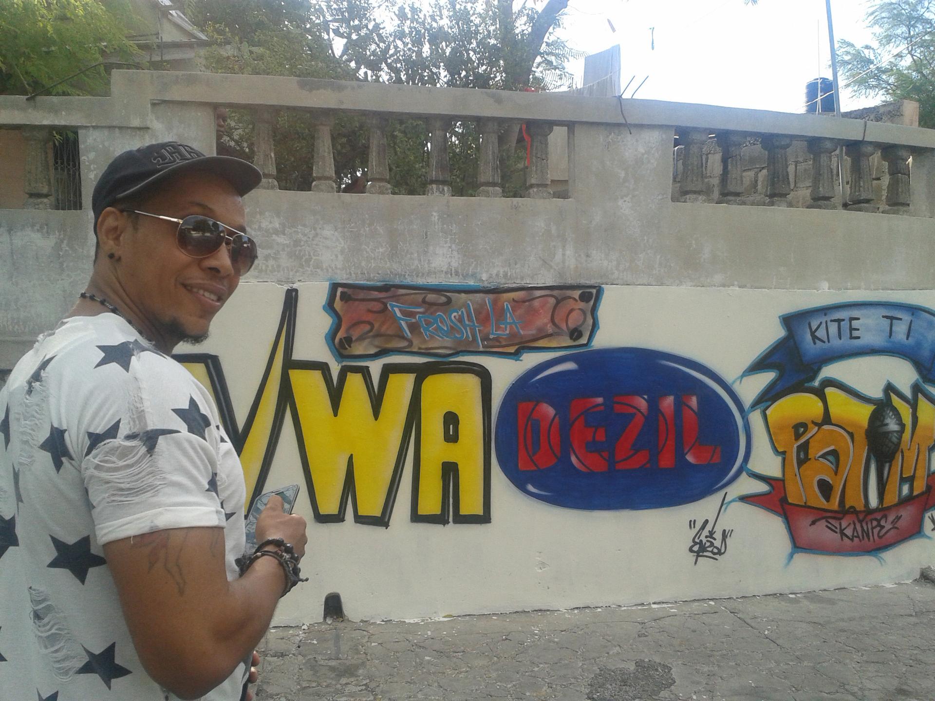 Freshla in front of a mural he commissioned in Delmas 5, Haiti