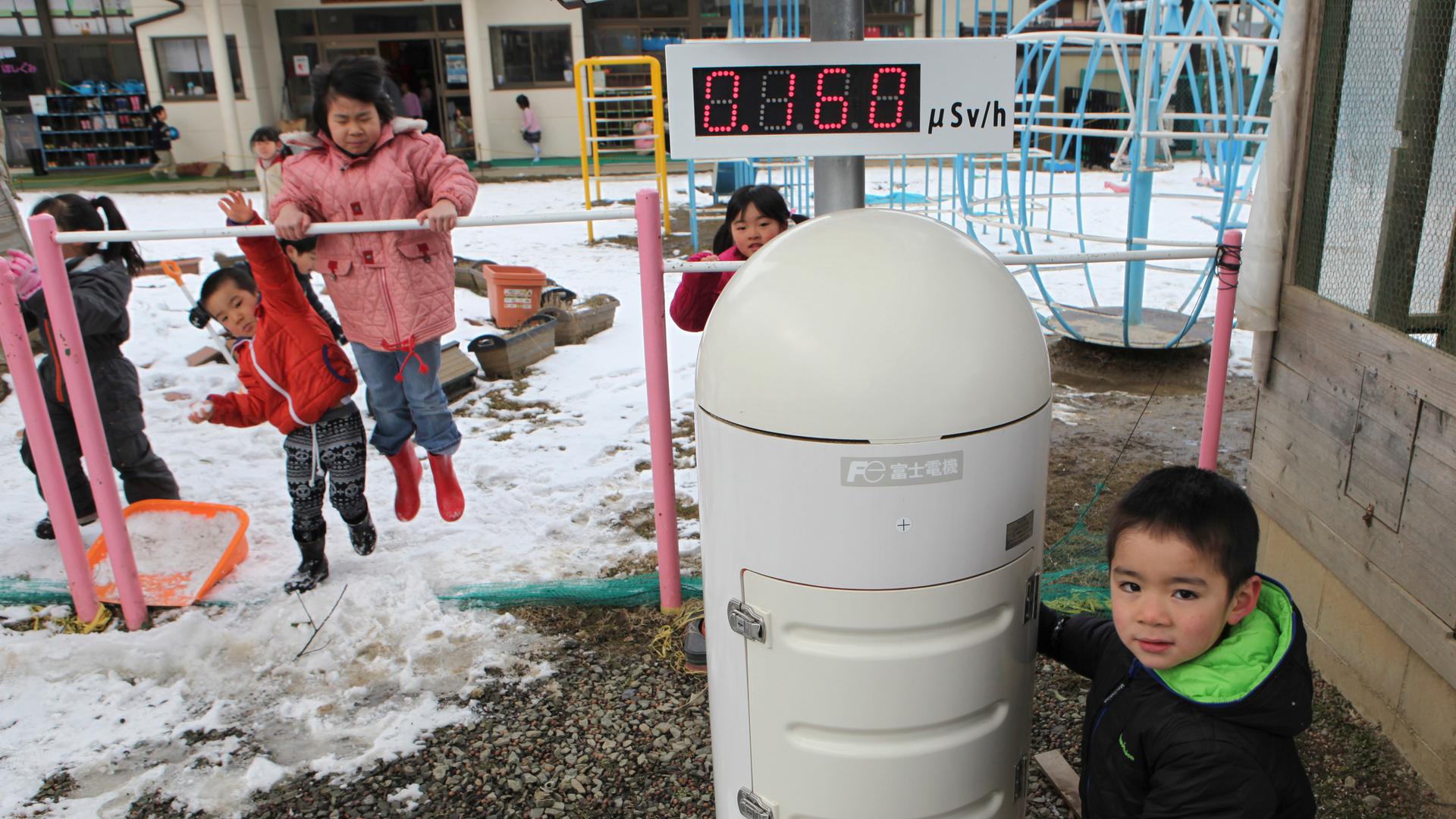 Children play near a Geiger counter that monitors radiation at a kindergarten about 30 miles from the tsunami-crippled Fukushima Daiichi nuclear power plant. The government is increasingly pushing families displaced by the disaster to return to their home