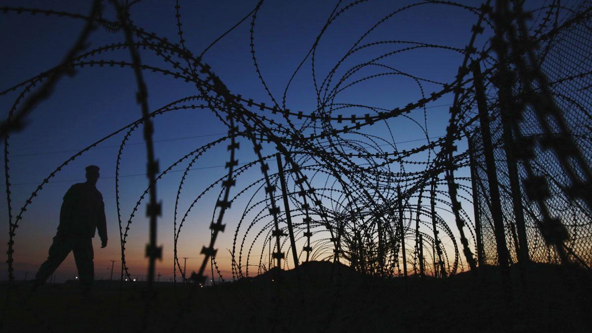 A soldier walks past concertina wire surrounding the outside of Joint Task Force Guantanamo's Camp Delta at the US Naval Base in Guantanamo Bay. 