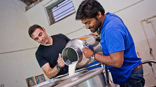 Sorin Grama, left, pours milk into his refrigeration system in India. 