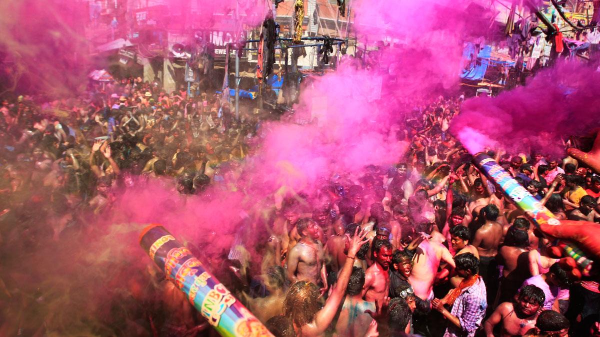 Men dance as others spray colored powder on them during Holi celebrations in India.