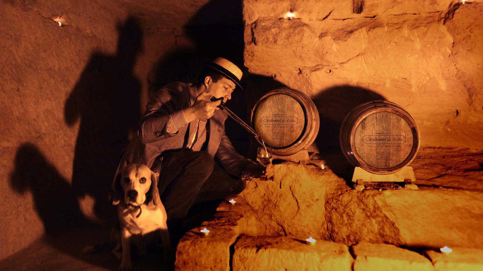 Audric de Campeau pours a glass of mead in the Paris catacombs with his dog, Filou.