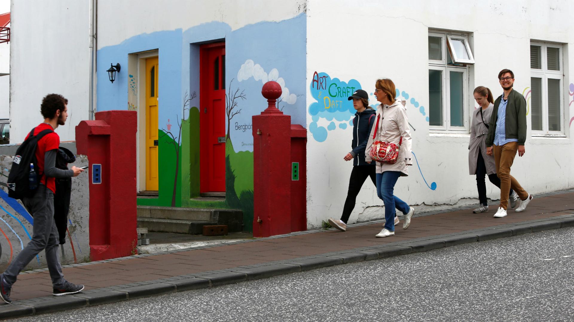 People walk pass pass a colorful house in Reykjavik, Iceland on August 4, 2017. 