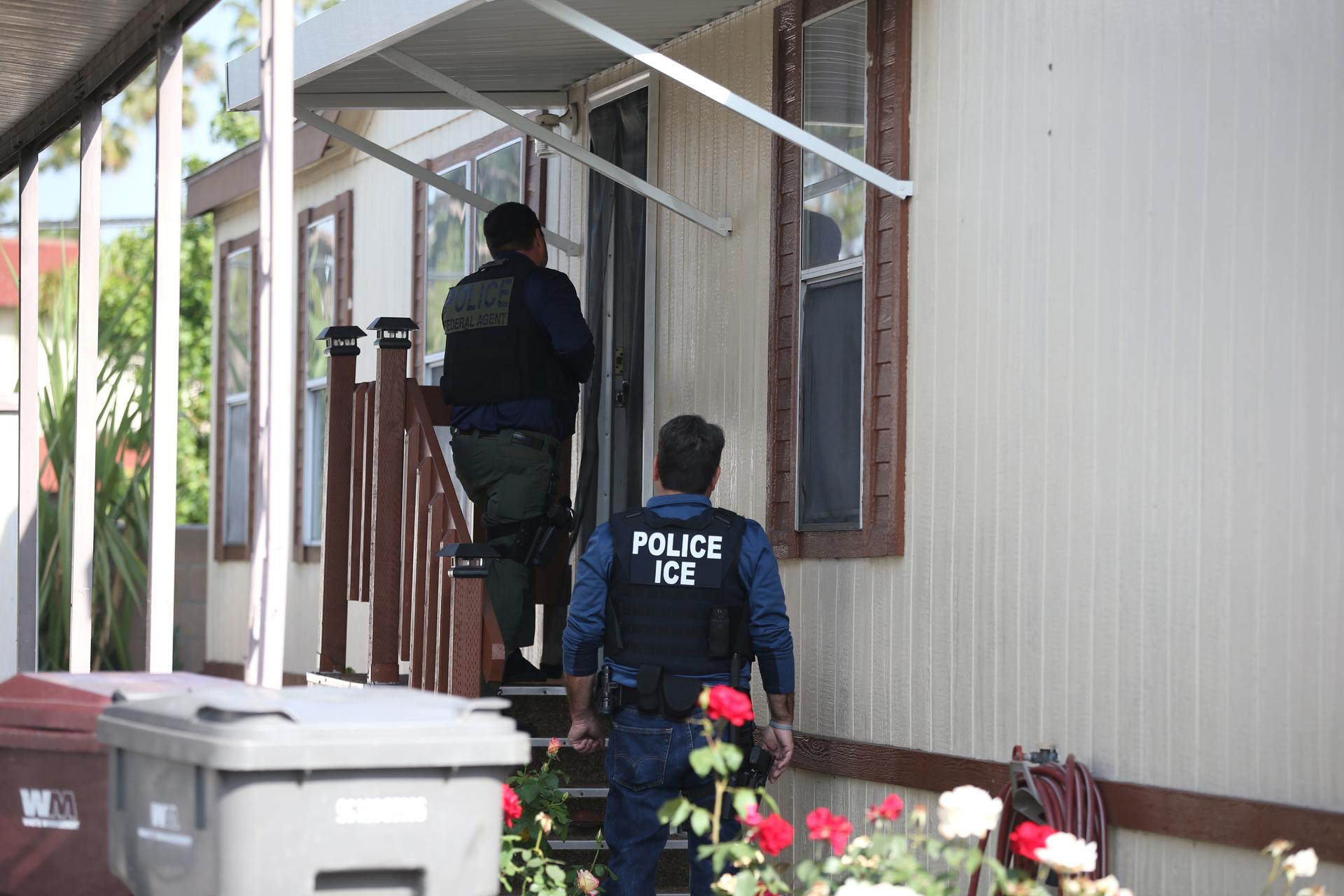 ICE agents knock on a door.