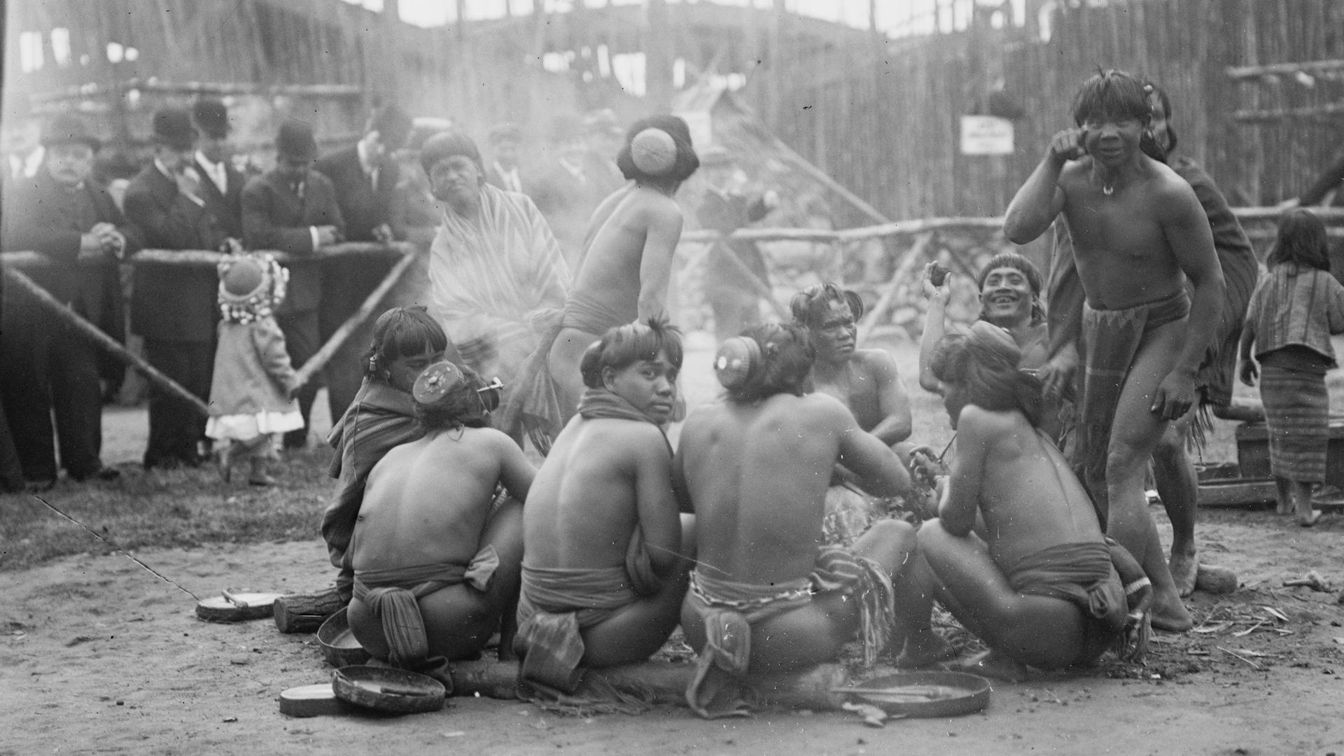 The Igorrotes sitting around a campfire, and playing up for the camera, at Coney Island in the summer of 1905.