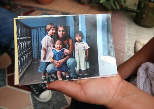 Loyda Rodríguez holding a photograph that shows her daughter Anyelí and her siblings.