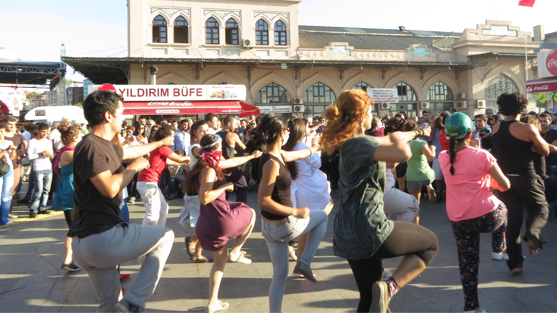 Flash mob protesters perform near an outdoor concert, just outside one of Istanbul's heavily used ferry stations.