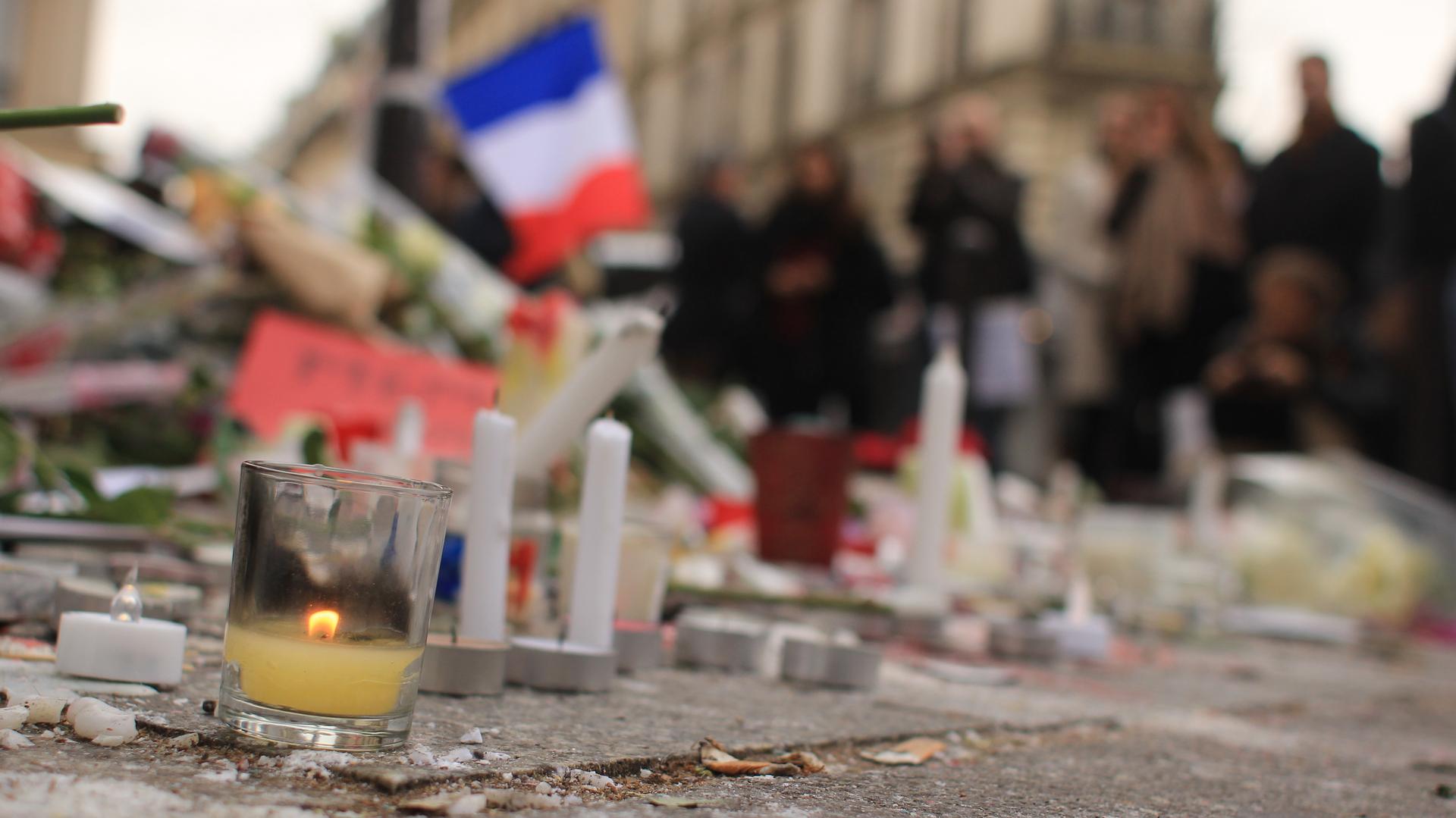 A candle outside Le Carillon bar in Paris, one of the scenes of Friday's attack, Hundreds of Parisians on Monday gathered there to pay their respects in silence.