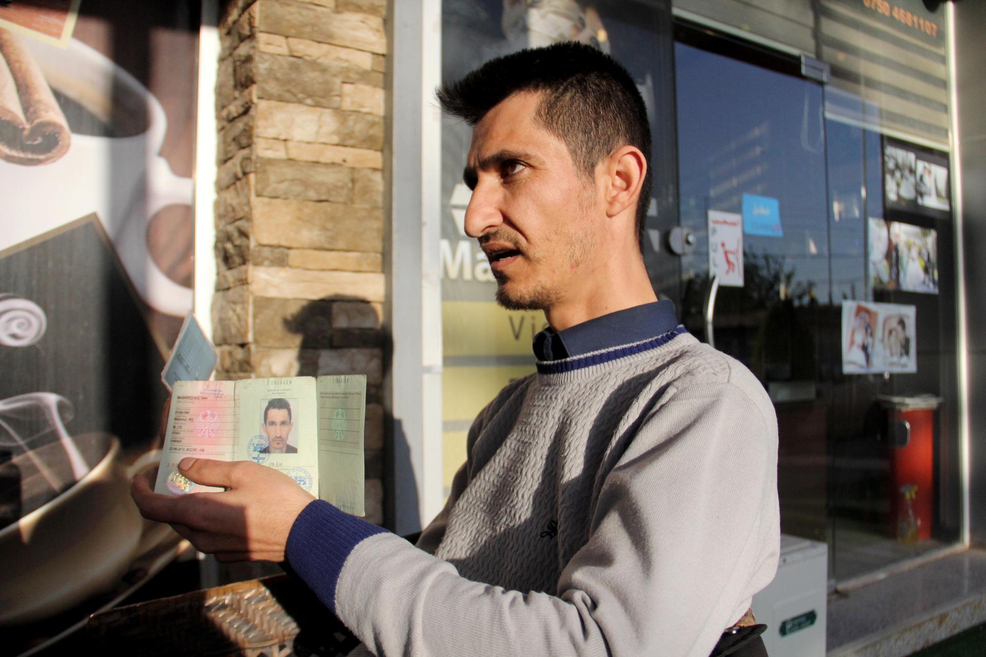 Dana Maghdeed Aziz holds up the identification issued to him by the Germany government.
