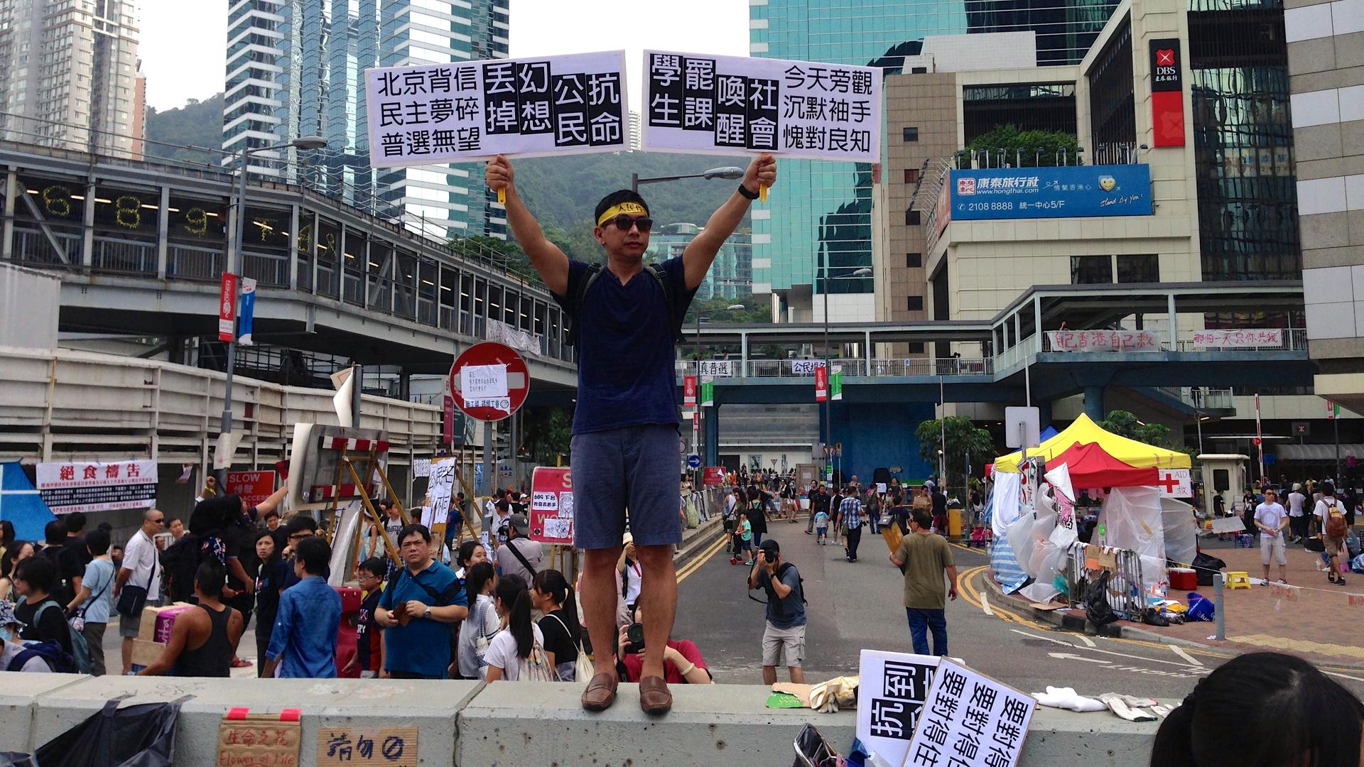 A protester's signs urged Hong Kong citizens to "wake up" and join demonstrations, because "Beijing is not trustworthy, and democracy is a broken dream".