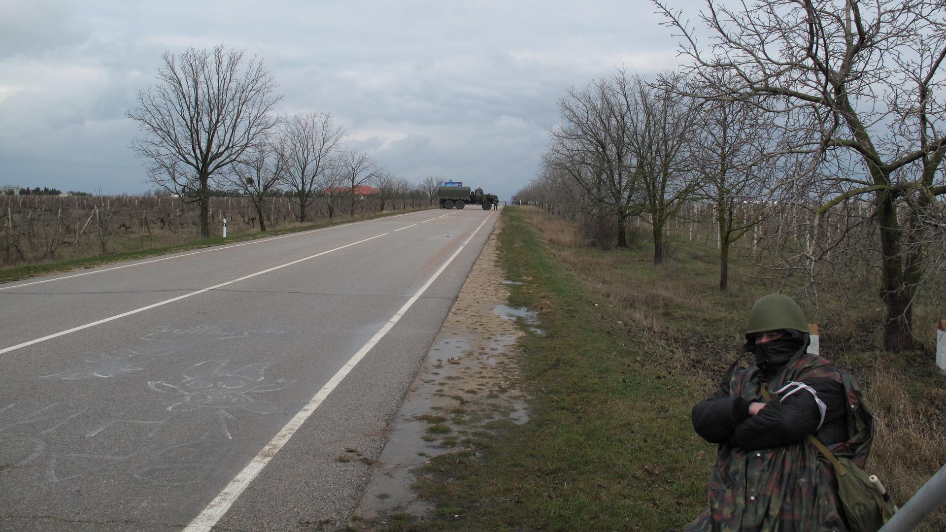 A militia man stands guard at a checkpoint Friday about a hundred yards from unmarked military trucks that have sealed off Sevastopol's airport. 