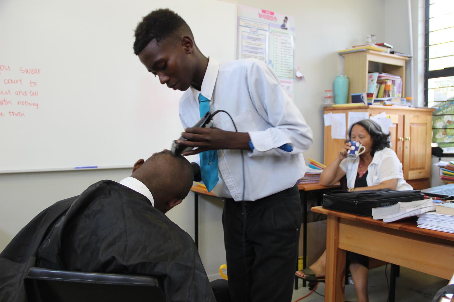Students at COSAT shave each other's heads