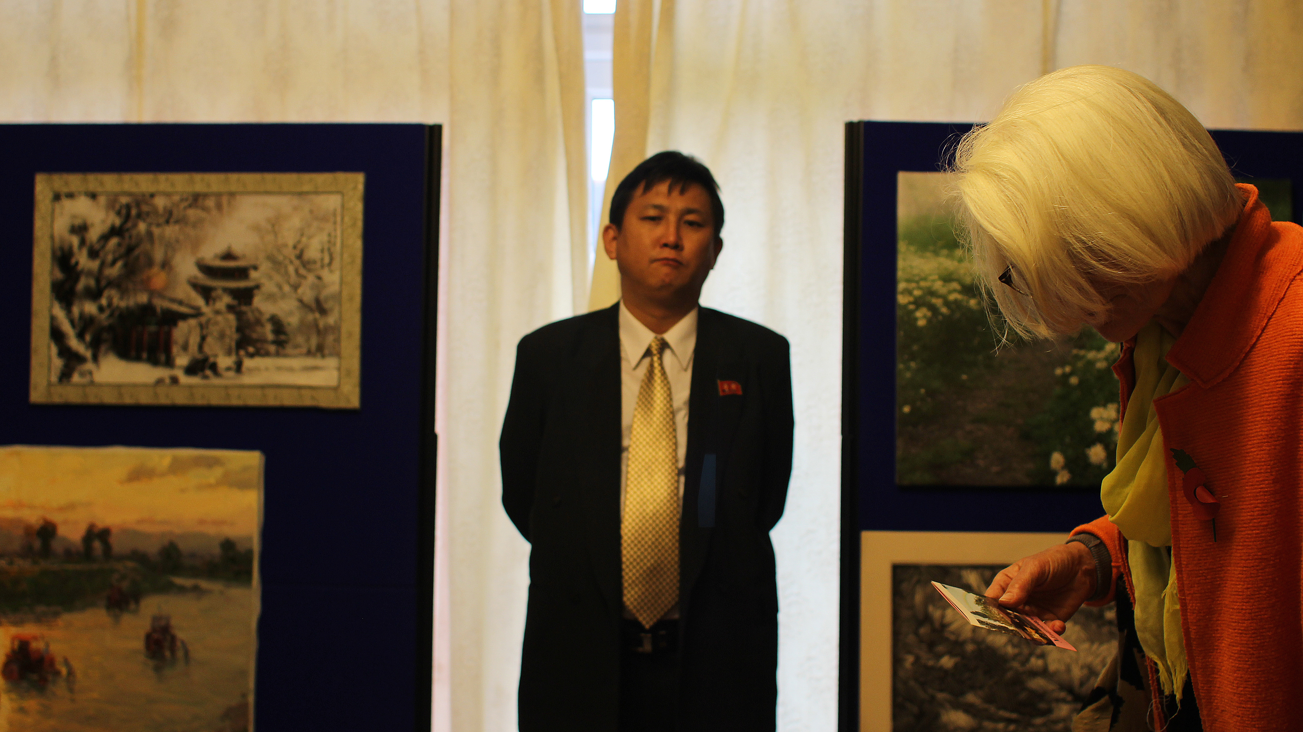 A North Korean official in London watches over visitors to the embassy's art exhibition